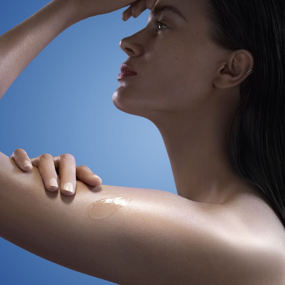 Siero applicato sul braccio. Trasparente, sulla pelle. Donna di profilo.