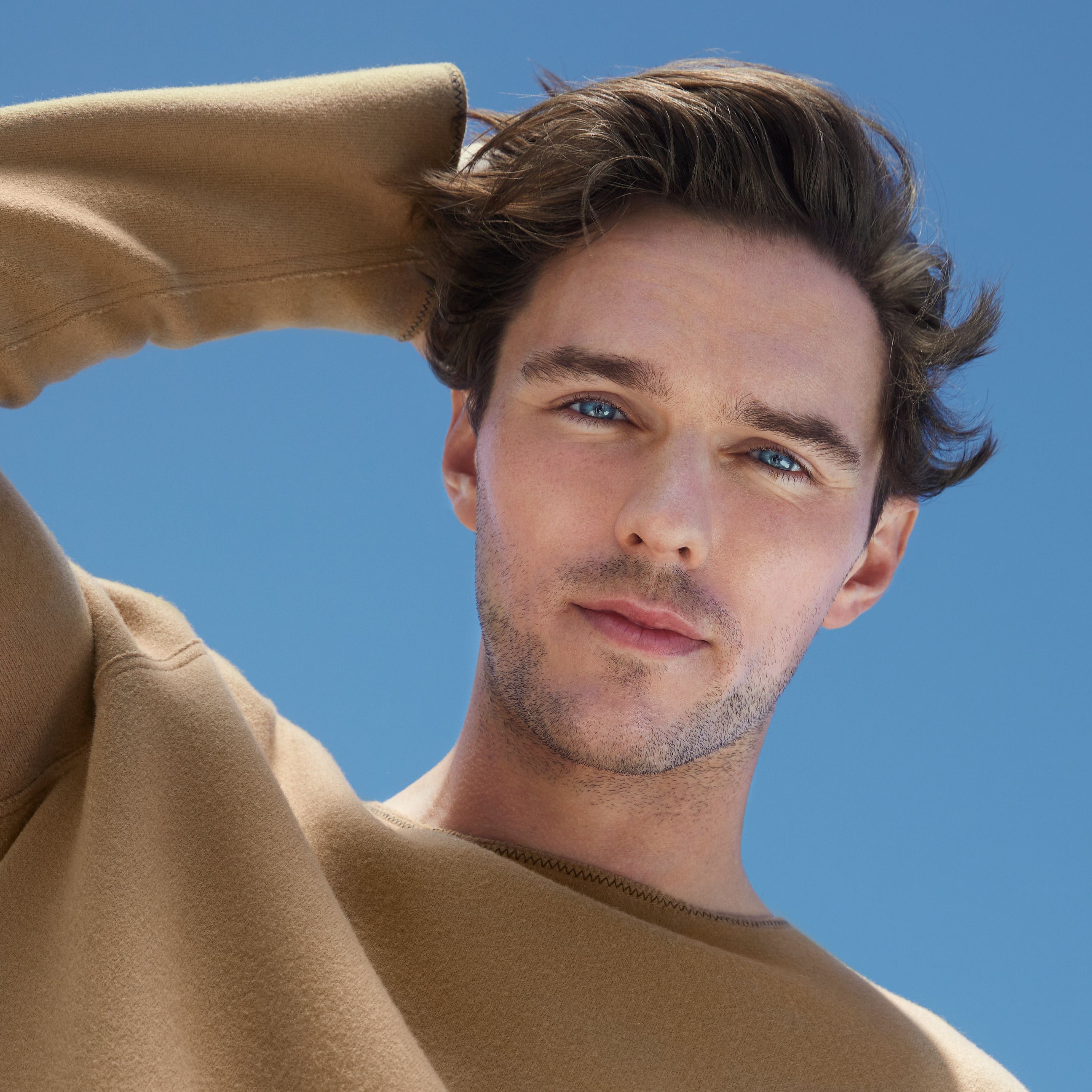 Un uomo con capelli castani e cielo blu sullo sfondo.