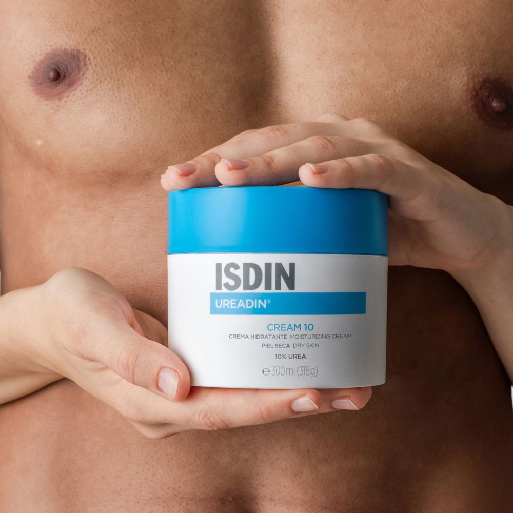 Mani che tengono un vaso di crema con coperchio blu. Scritta: ISDIN UREADIN CREAM 10.