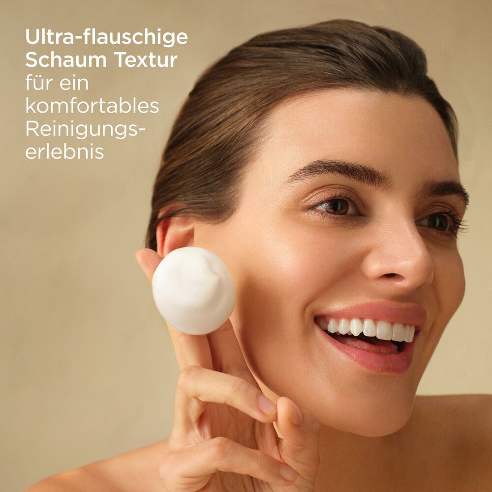 Donna con schiuma in mano. Testo: Texture schiuma ultra-morbida per un'esperienza di pulizia confortevole.