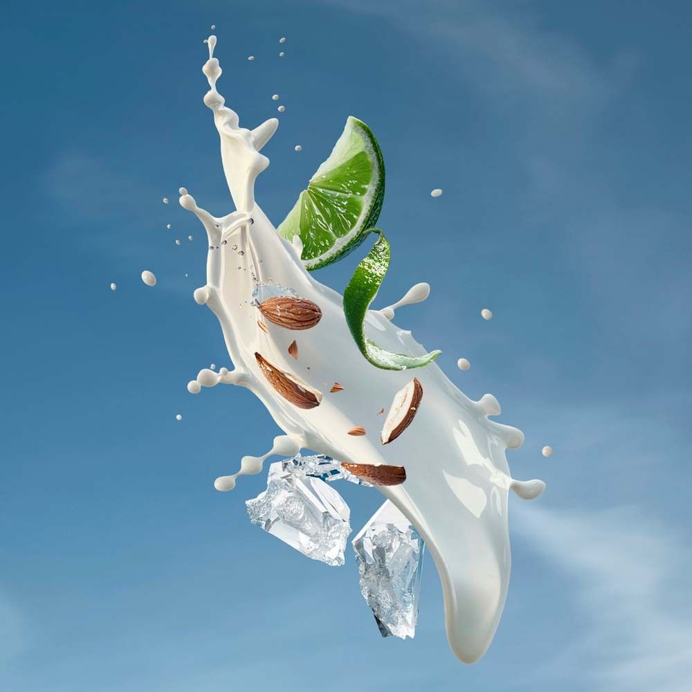 Schizzo di latte con fetta di lime, scaglie di mandorle e cubetti di ghiaccio, cielo blu.