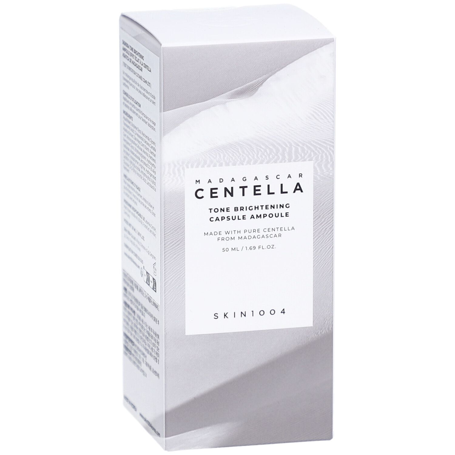 Confezione bianca con informazioni sul prodotto. Testo: MADAGASCAR CENTELLA Tone Brightening Capsule Ampoule. Logo SKIN1004.