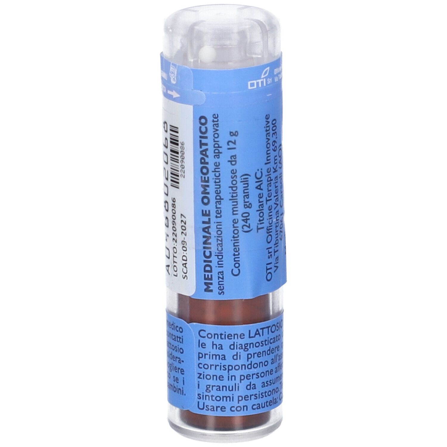 Flacone cilindrico multidose. Etichetta blu e bianca con testo. Tappo trasparente. Granuli marroni visibili.
