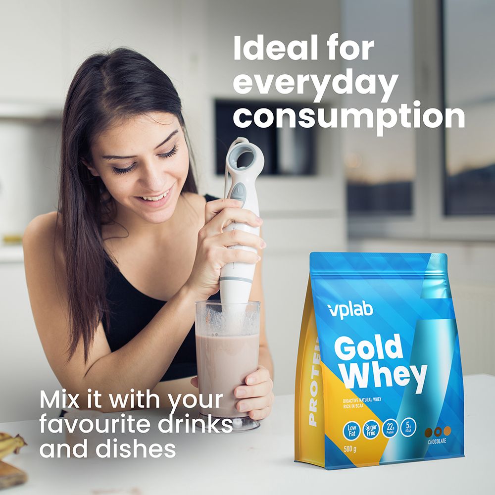Donna mescola bevanda con confezione 'Gold Whey'. Testo: 'Ideale per il consumo quotidiano'. Prodotto sul tavolo.