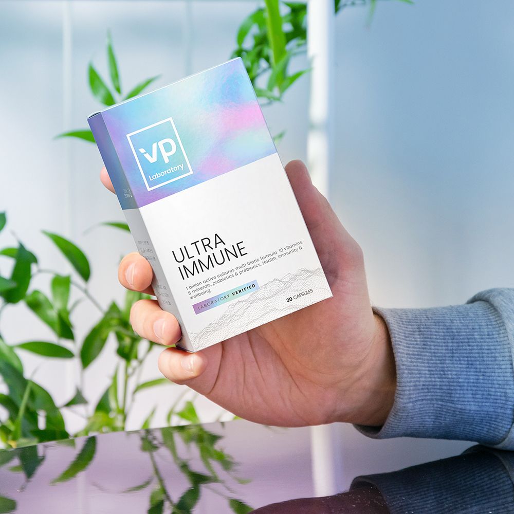 Mano che tiene la confezione Ultra Immune. Nome e logo del prodotto visibili. Confezione con effetto olografico.