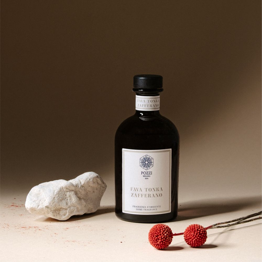 Bottiglia di vetro marrone con tappo nero. Etichetta bianca. Decorazione: pietra, sfere rosse. Prodotto: Fava Tonka Zafferano.