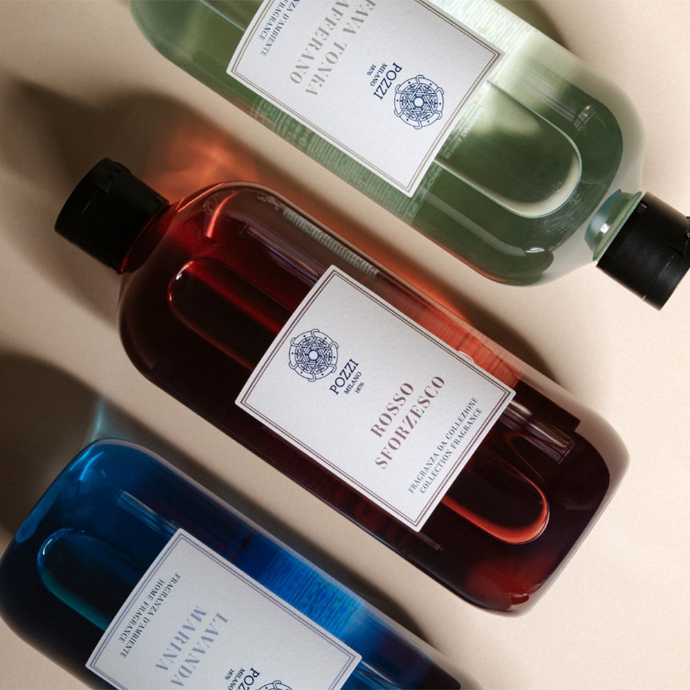 Tre bottiglie di liquido. Etichette con testo: Pozzi Milano. Colori: blu, rosso, verde.