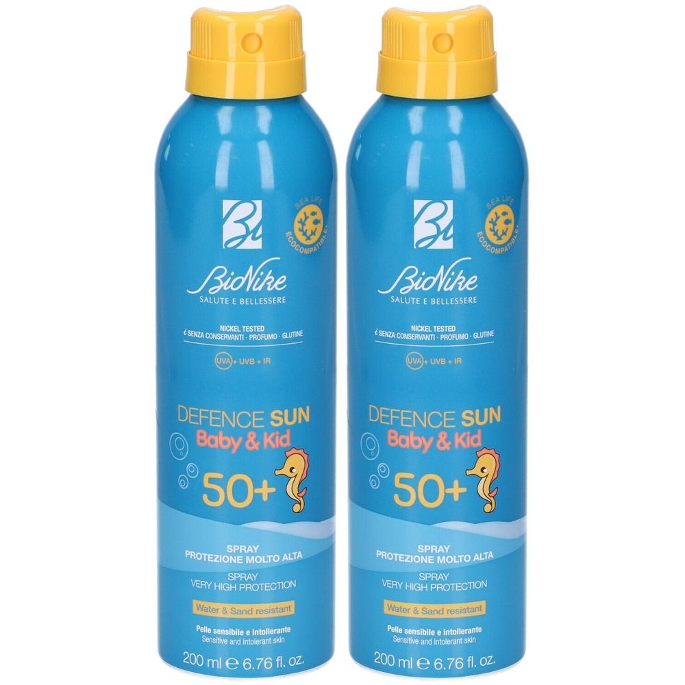 Due flaconi spray blu con tappi gialli. Scritta: BioNike Defence Sun Baby & Kid 50+. Protezione molto alta. Resistente all'acqua e alla sabbia.