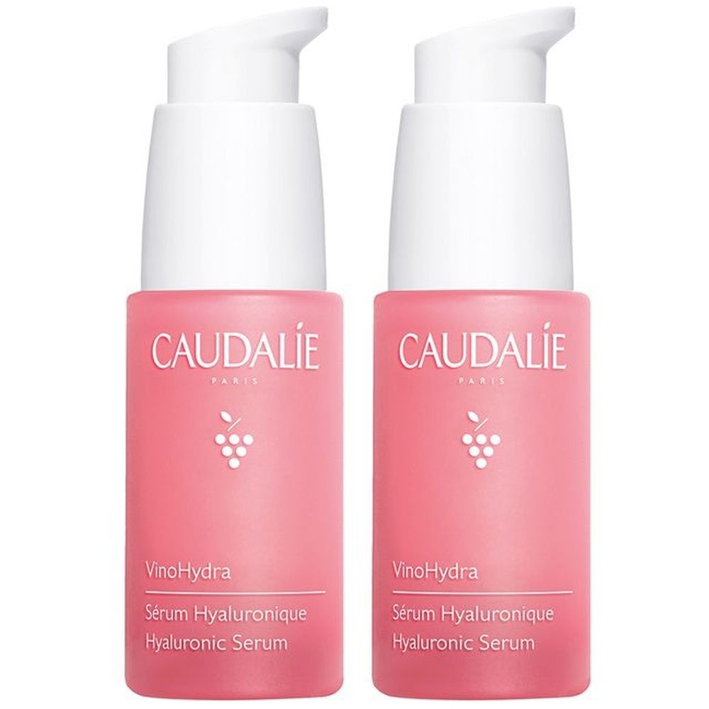 Due flaconi rosa con erogatori bianchi. Su ogni flacone, la scritta "CAUDALIE" e "VinoHydra". Sotto, "Sérum Hyaluronique".
