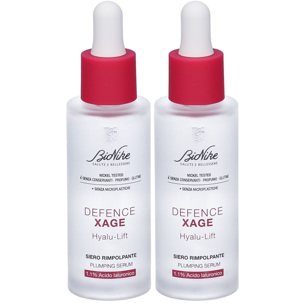 Due flaconi di siero. Vetro bianco, tappo rosso, contagocce. Scritta: Defence Xage, Hyalu-Lift, Siero Rimpolpante, 1.1% Acido Ialuronico.