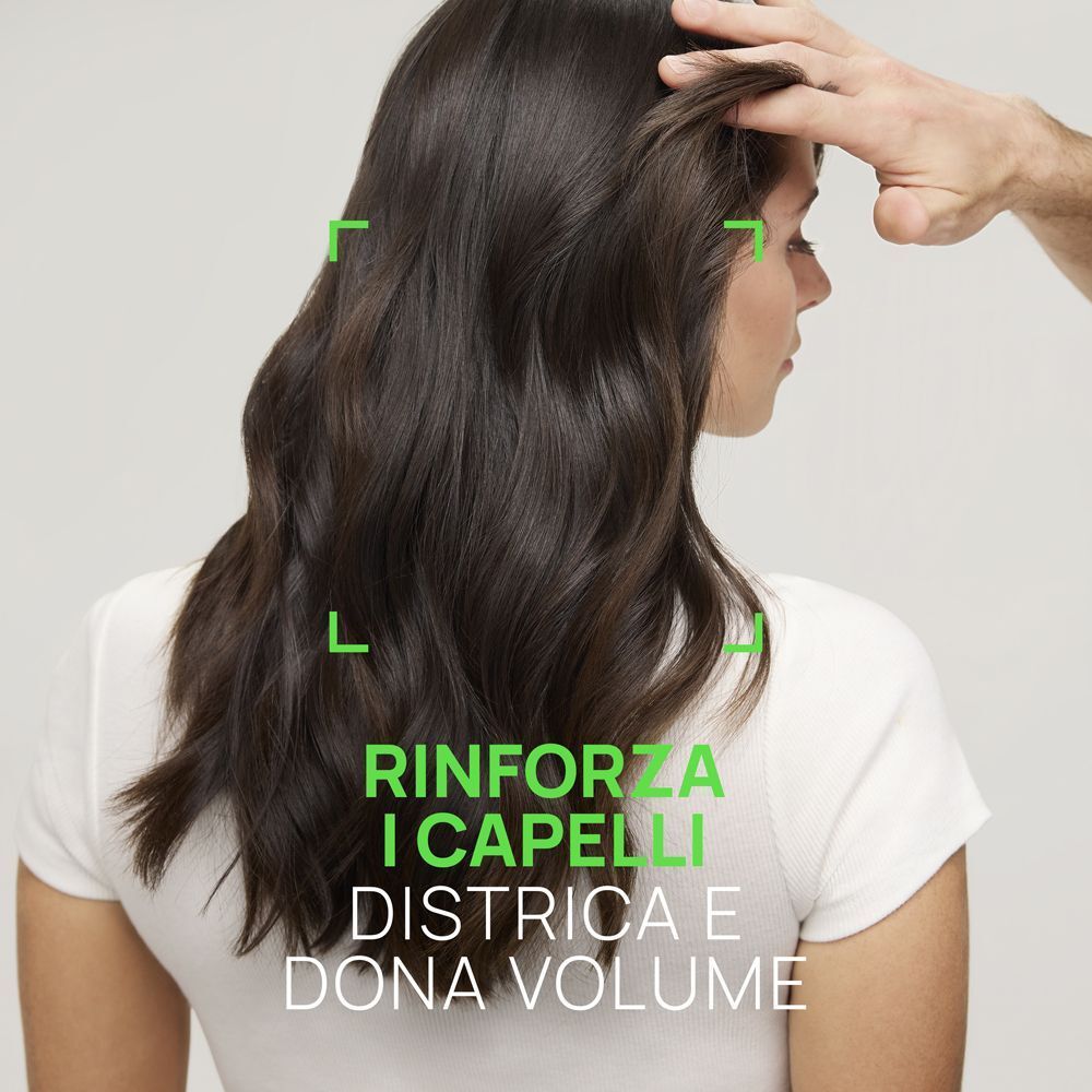 Donna con capelli lunghi e scuri. Testo: Rinforza i capelli, districa e dona volume.