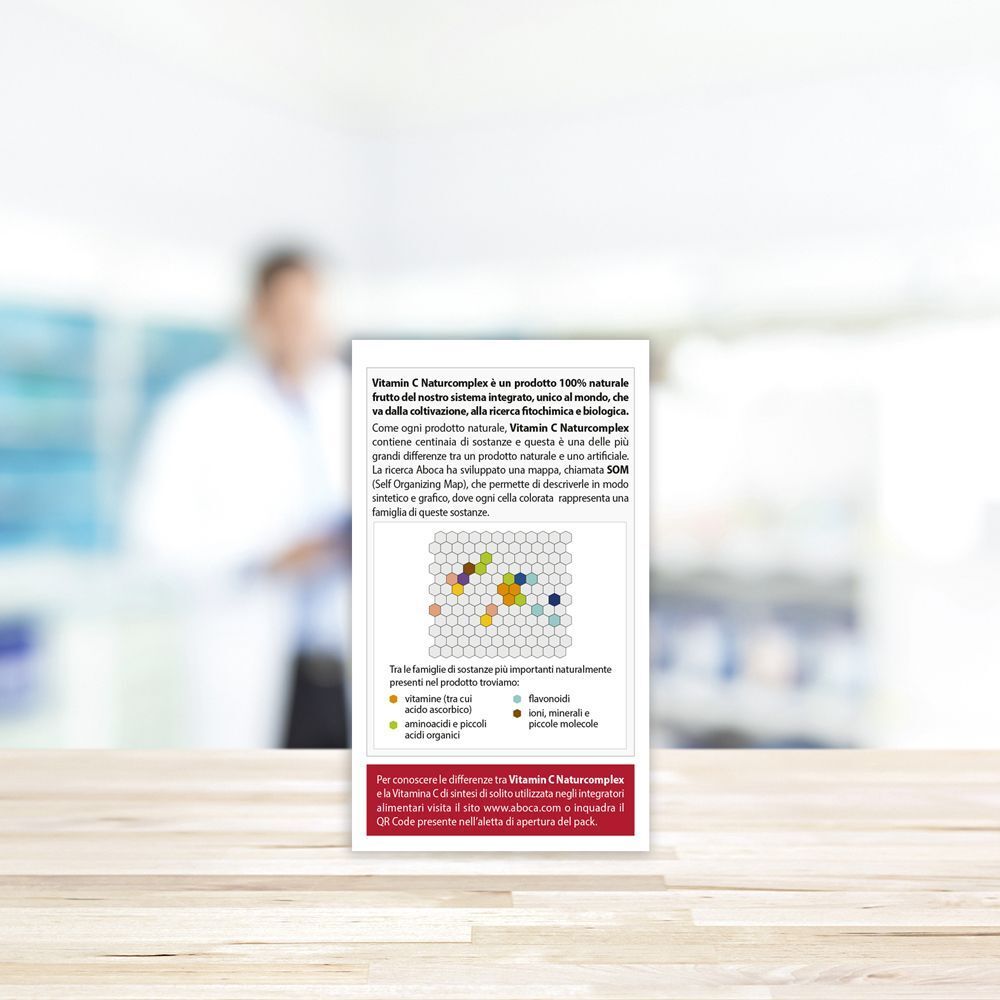 Retro della confezione Vitamin C Naturcomplex. Testo e diagramma con ingredienti. Sfondo: persona sfocata.