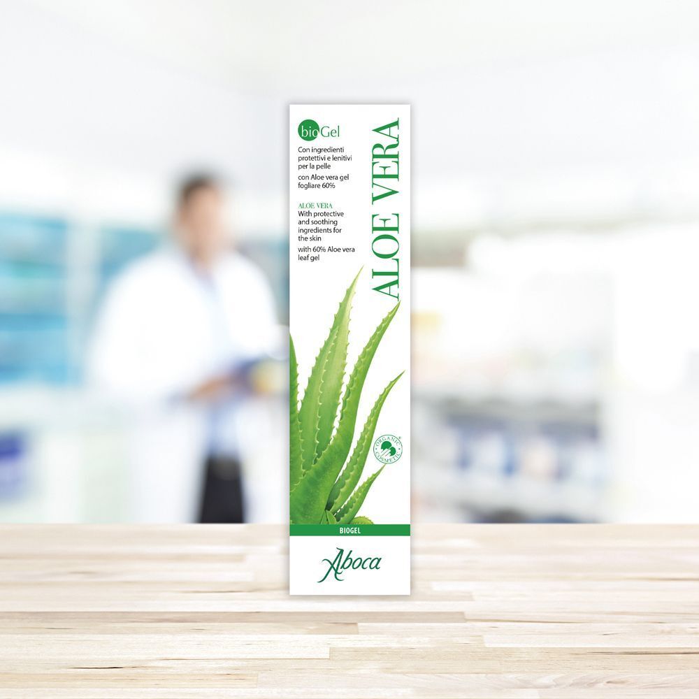 Confezione di gel di aloe vera. Scatola verde e bianca con illustrazione di foglie di aloe vera e testo. Marchio: Aboca. Sfondo: farmacia.