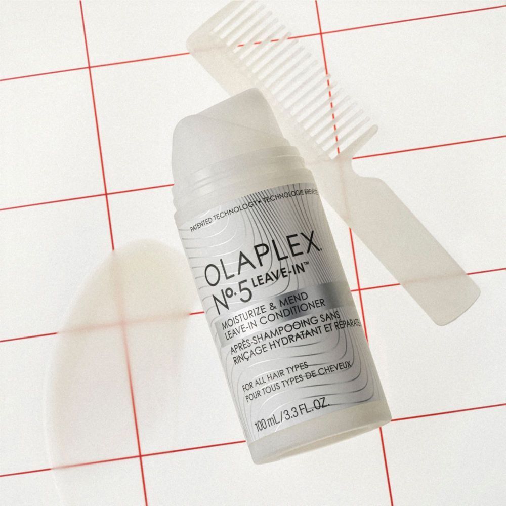 Un flacone di Olaplex N°.5 Leave-In Conditioner accanto a un pettine trasparente.