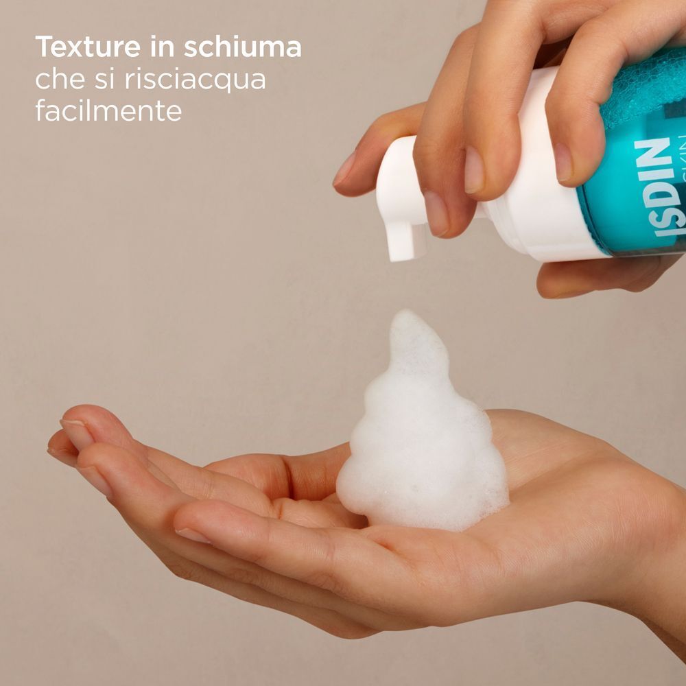 Una mano riceve schiuma da un flacone di mousse detergente ISDIN Acniben. Texture leggera in schiuma.