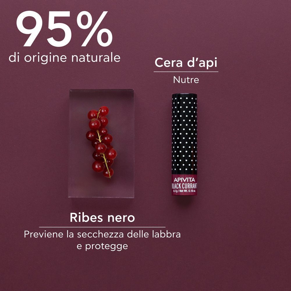 Balsamo labbra accanto a un bicchiere di ribes nero. 95% di origine naturale.