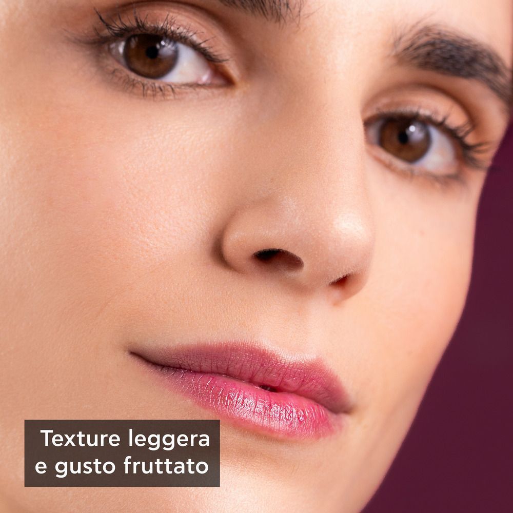 Primo piano di una donna che indossa un balsamo labbra dalla texture leggera e gusto fruttato.