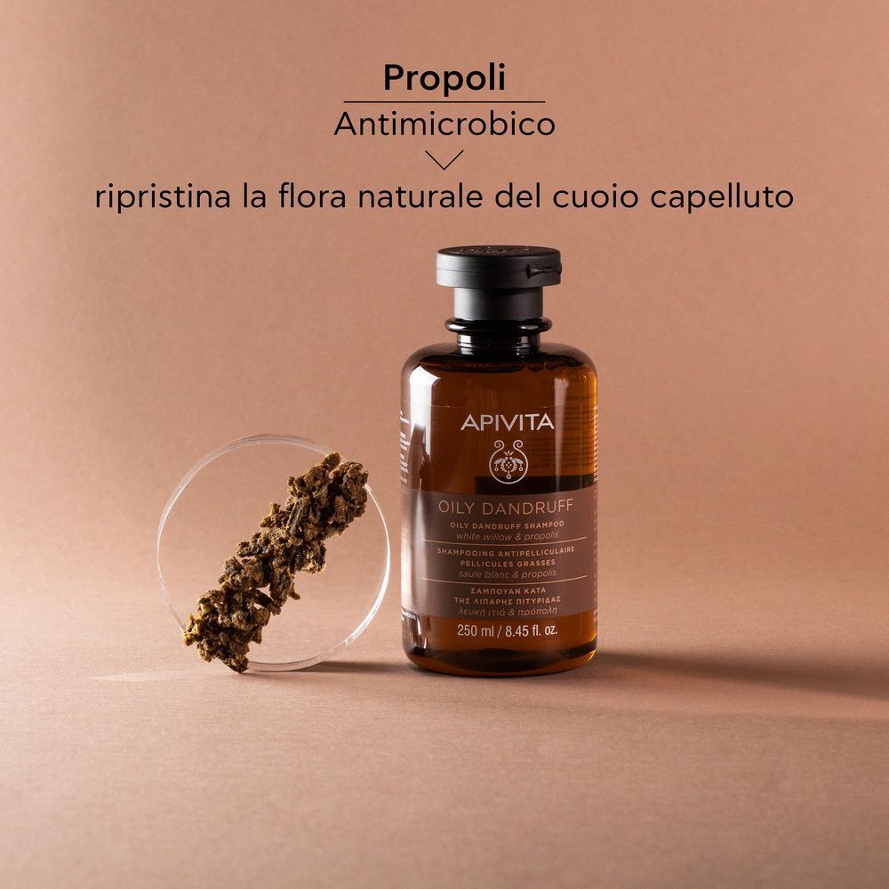 Flacone di shampoo APIVITA accanto a grani di propoli, antimicrobico.