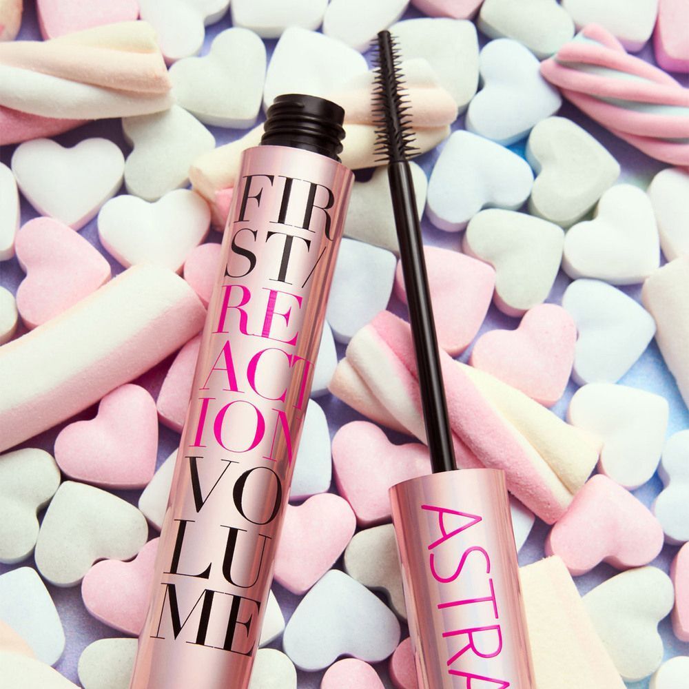 Un flacone di mascara Astra e un pennello adagiati su caramelle.