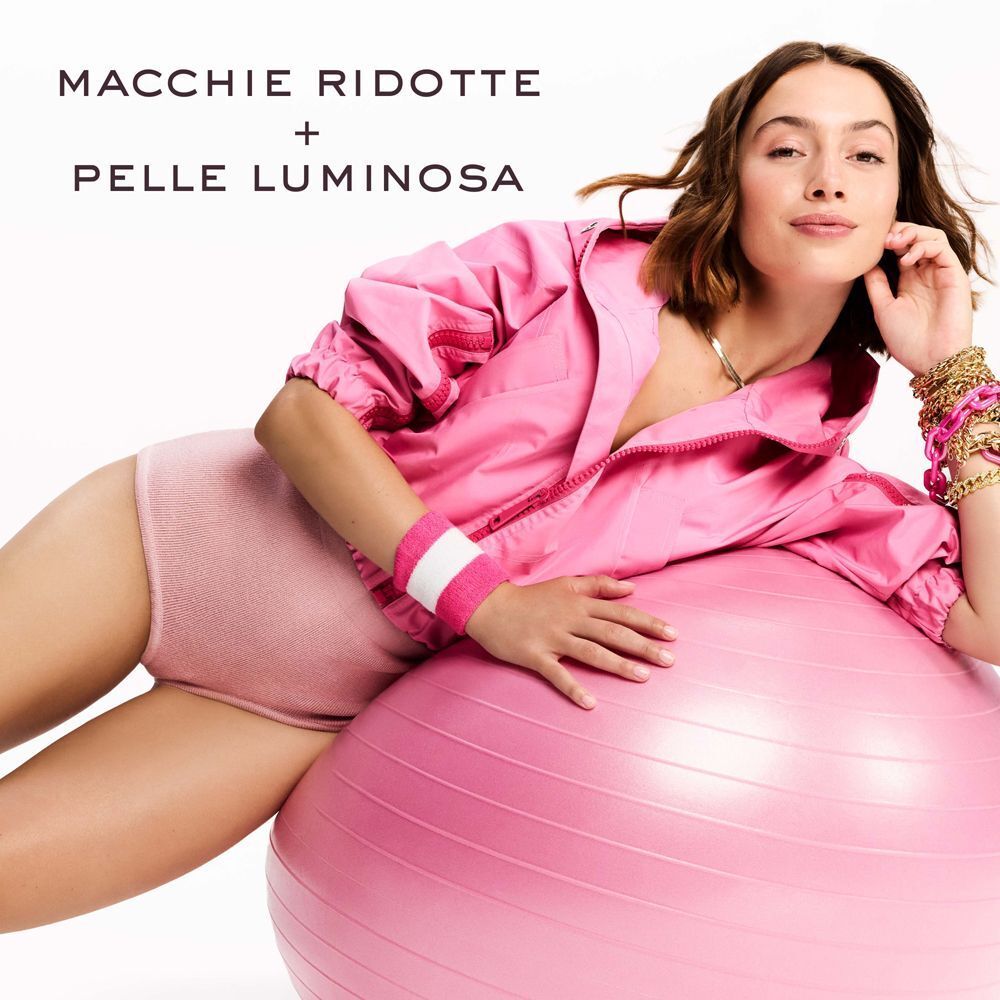 Donna con un pallone da ginnastica, testo: "Macchie ridotte + pelle luminosa".