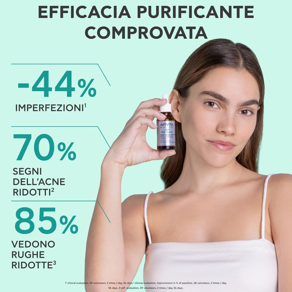 Donna tiene in mano un flacone di siero Apivita Just Bee Clear. Testo: 'Efficacia Purificante Comprovata'.