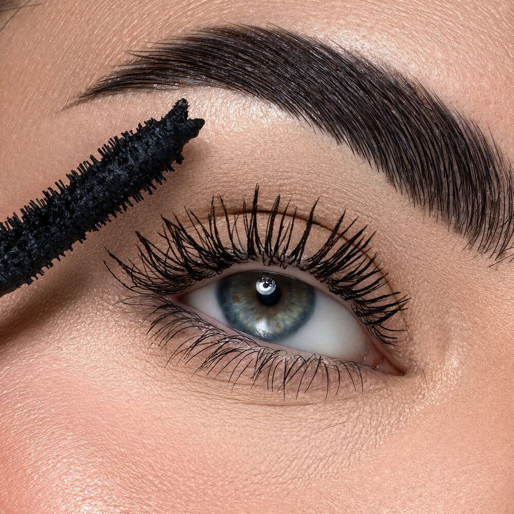 Un occhio con mascara applicato e un applicatore di mascara.