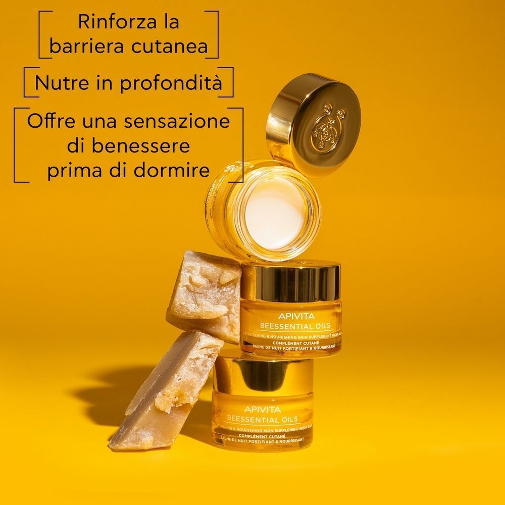 Un vasetto aperto Apivita Beessentials Oils Balsamo Notte con balsamo, accanto due vasetti chiusi e pezzi di favo.