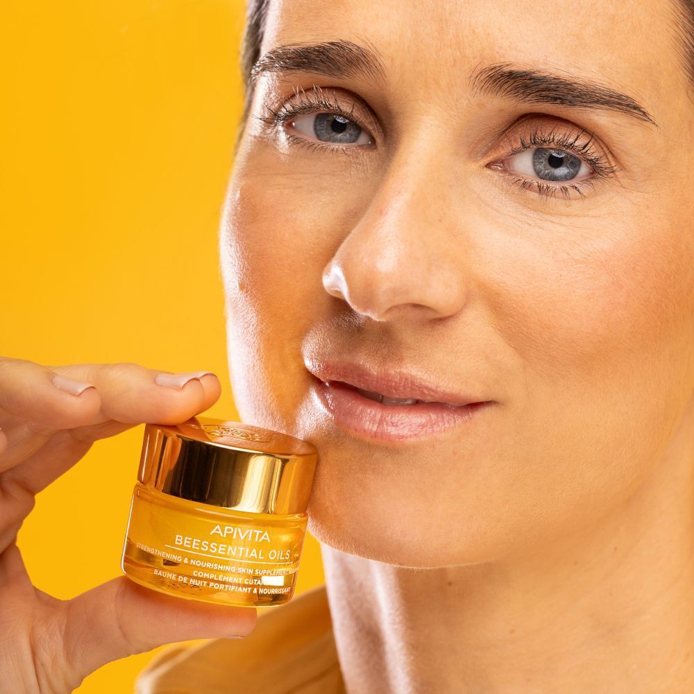 Donna tiene in mano un vasetto di Apivita Beessentials Oils Balsamo Notte.