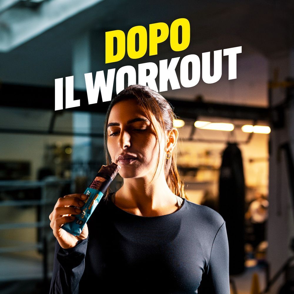 Donna mangia una barretta proteica ENERVIT dopo l'allenamento.