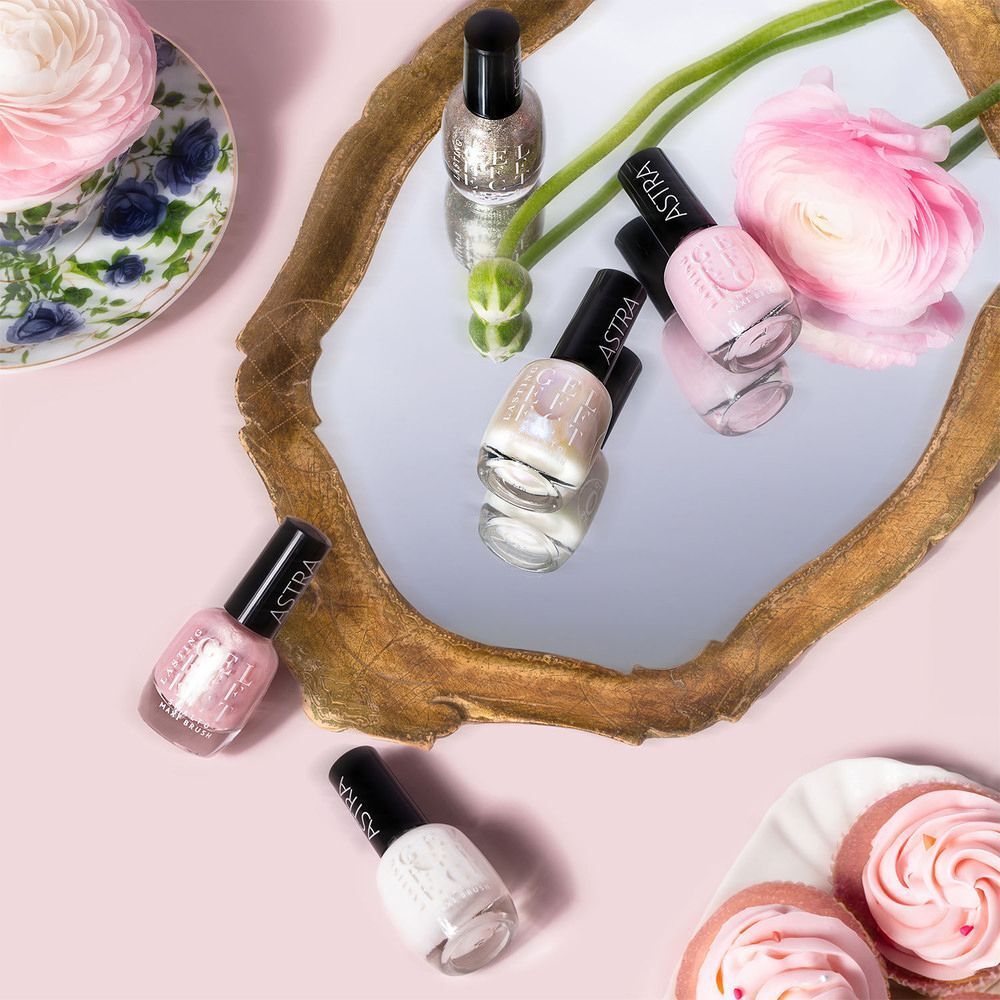 Diverse boccette di smalto Astra in varie tonalità di rosa su uno specchio.