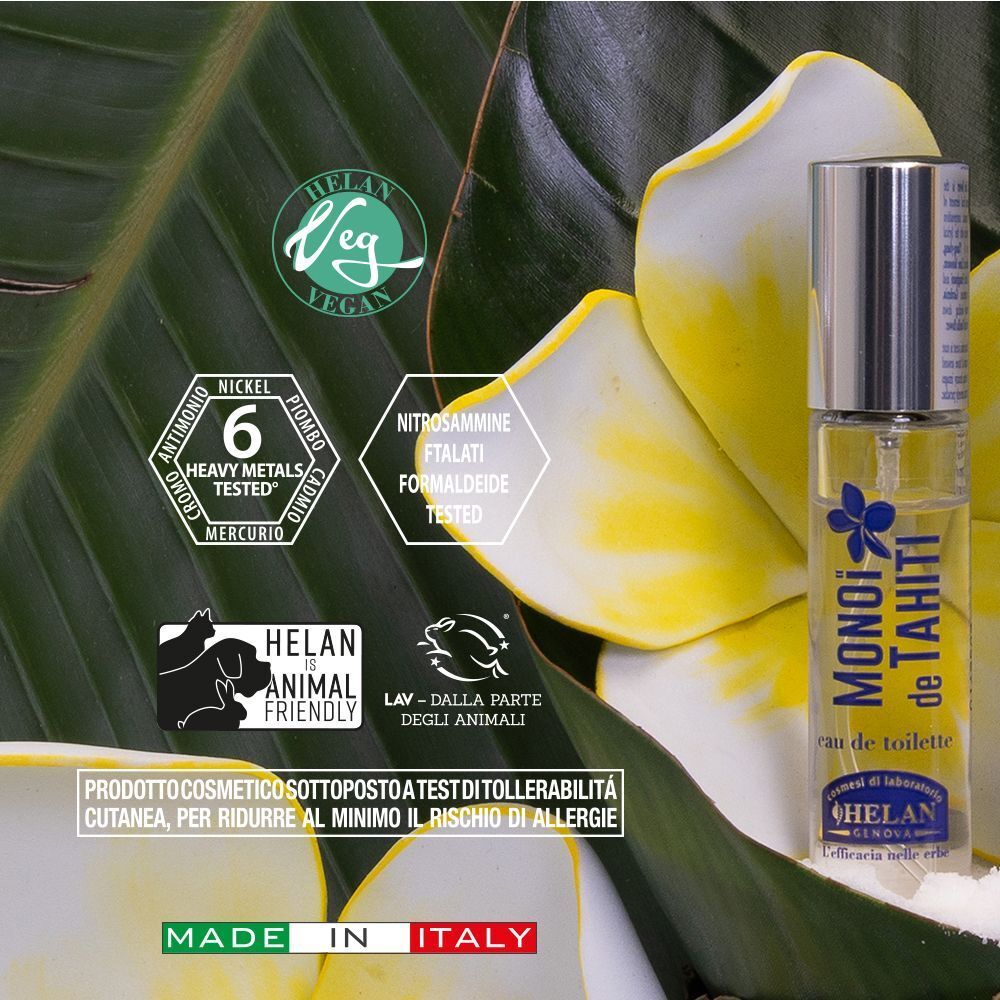 Un flacone in vetro di eau de toilette e la sua scatola di imballaggio, disposti con foglie e fiori tropicali.