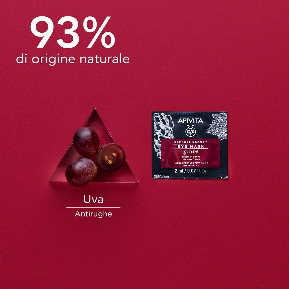 Bustina di maschera per occhi accanto a tre acini d'uva tagliati su un piatto triangolare.