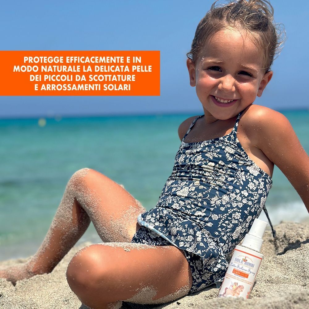 Bambina sulla spiaggia con flacone spray Helan Sole Bimbi Latte Solare SPF 50+.
