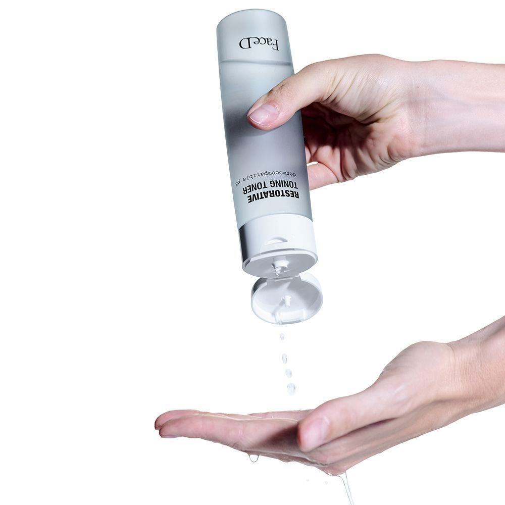 Liquido da un flacone di Face D Restorative Toning Toner versato nel palmo di una mano.