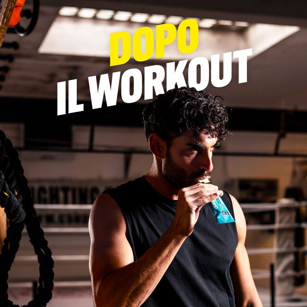 Uomo mangia barretta proteica ENERVIT dopo allenamento in palestra.