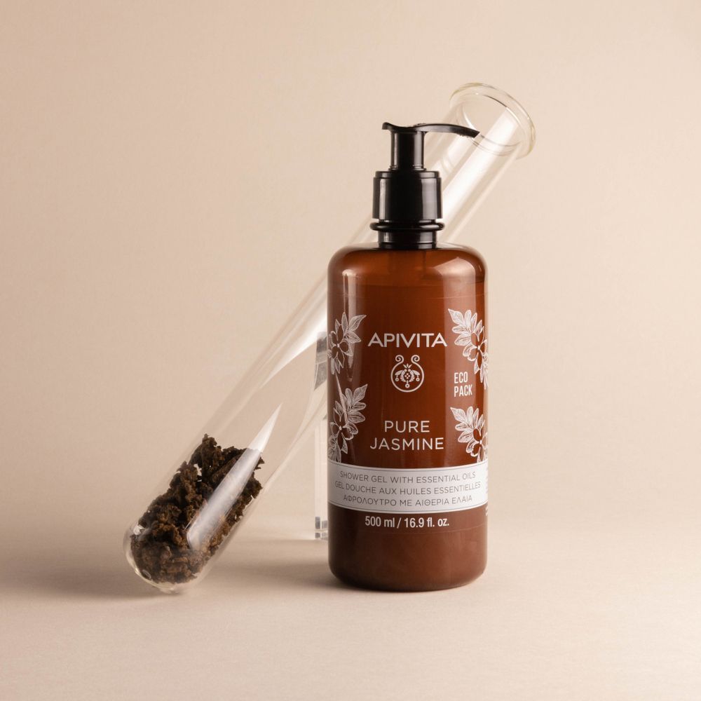 Gel doccia APIVITA PURE JASMINE in flacone con pompa marrone vicino a provetta con propoli.