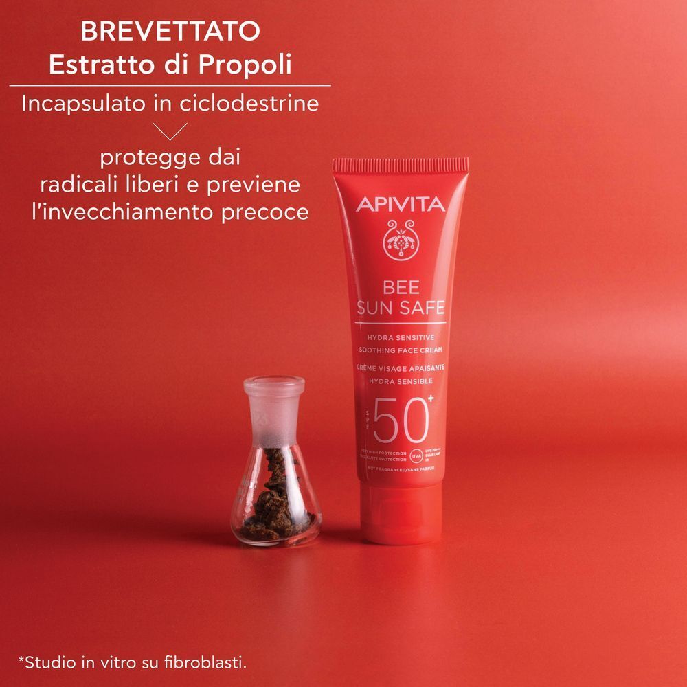 Tubo rosso di crema viso solare SPF 50+, vicino a un pallone con estratto di propoli.