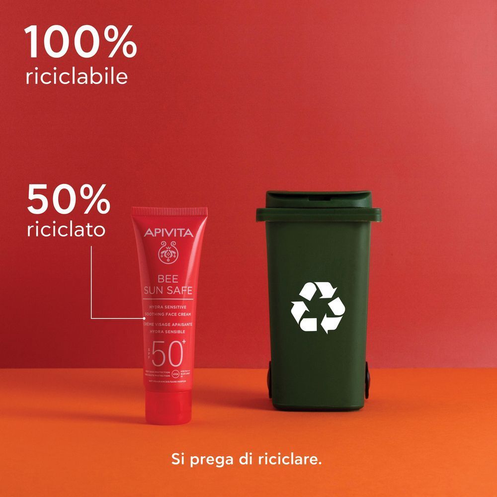 Tubo rosso di crema viso solare SPF 50+, accanto a un bidone verde per il riciclaggio.