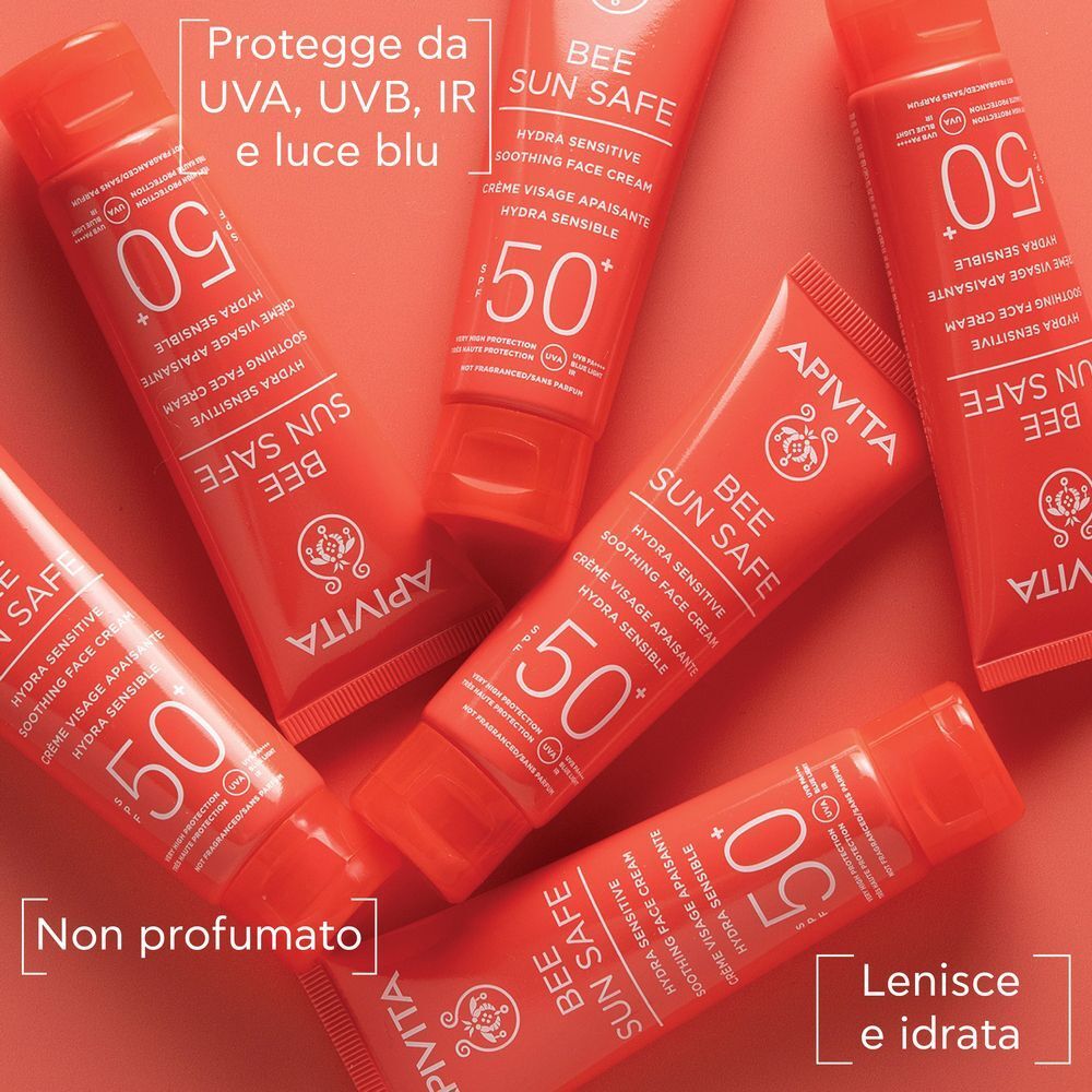 Vari tubetti rossi di crema solare viso APIVITA SPF 50+ su sfondo rosso.