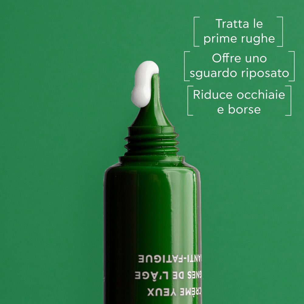 Primo piano del tubetto aperto con crema contorno occhi applicata. Testo in italiano.
