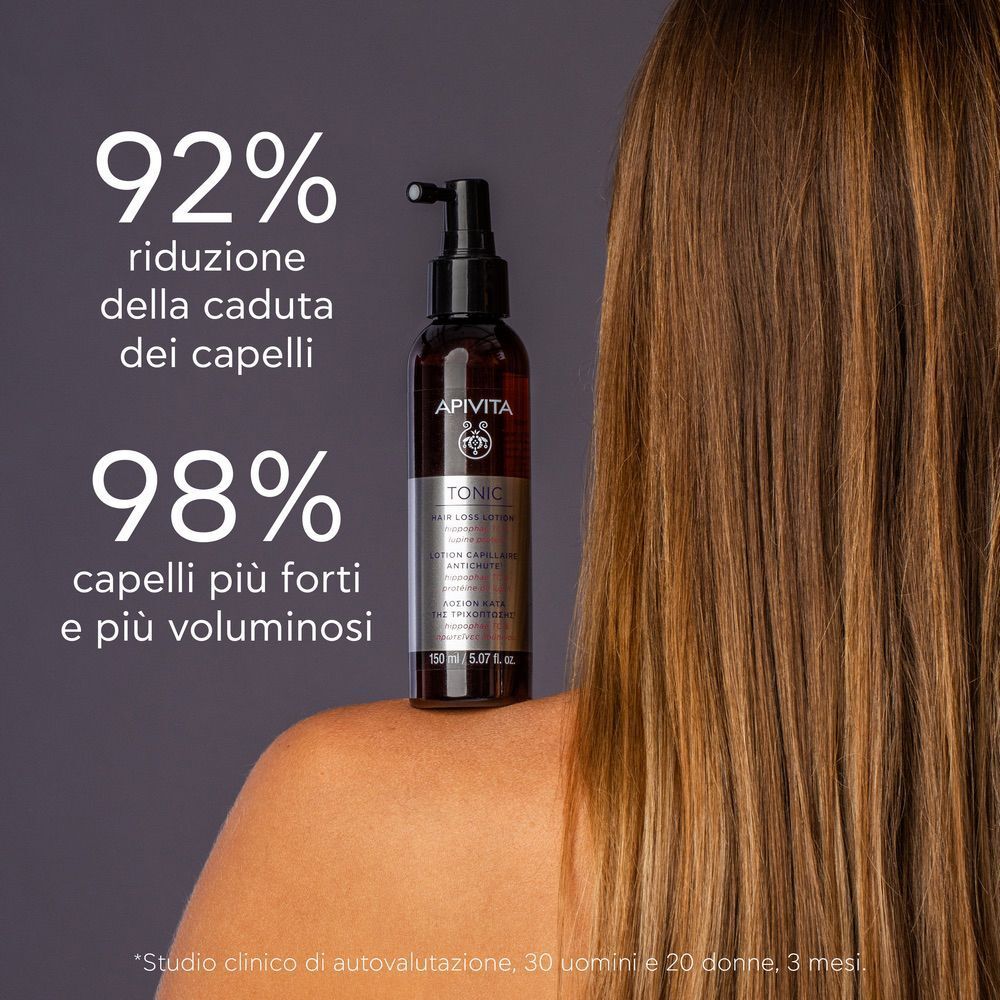 Donna con capelli lunghi tiene un flacone di lozione APIVITA TONIC. 92% in meno di caduta capelli.