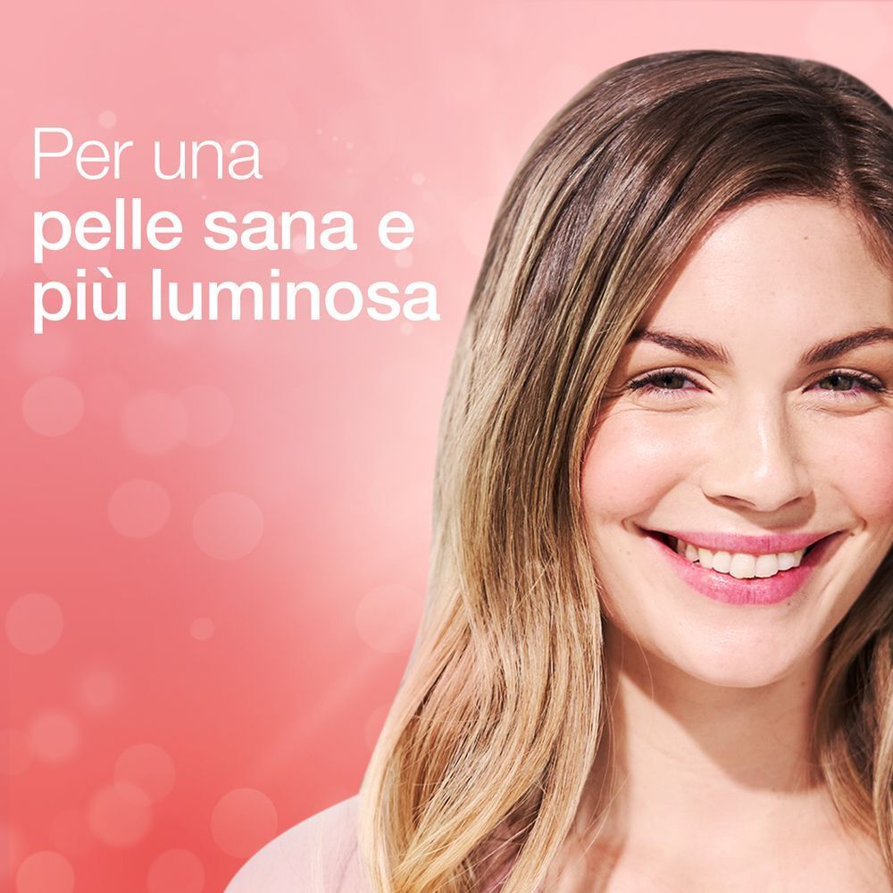 Donna sorridente con pelle luminosa su sfondo rosa.