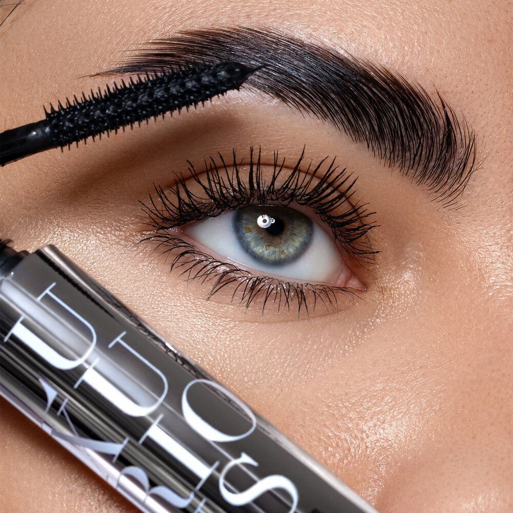 Primo piano di un occhio a cui viene applicato il mascara. Visibili la spazzola e parte del tubetto di mascara ASTRA.