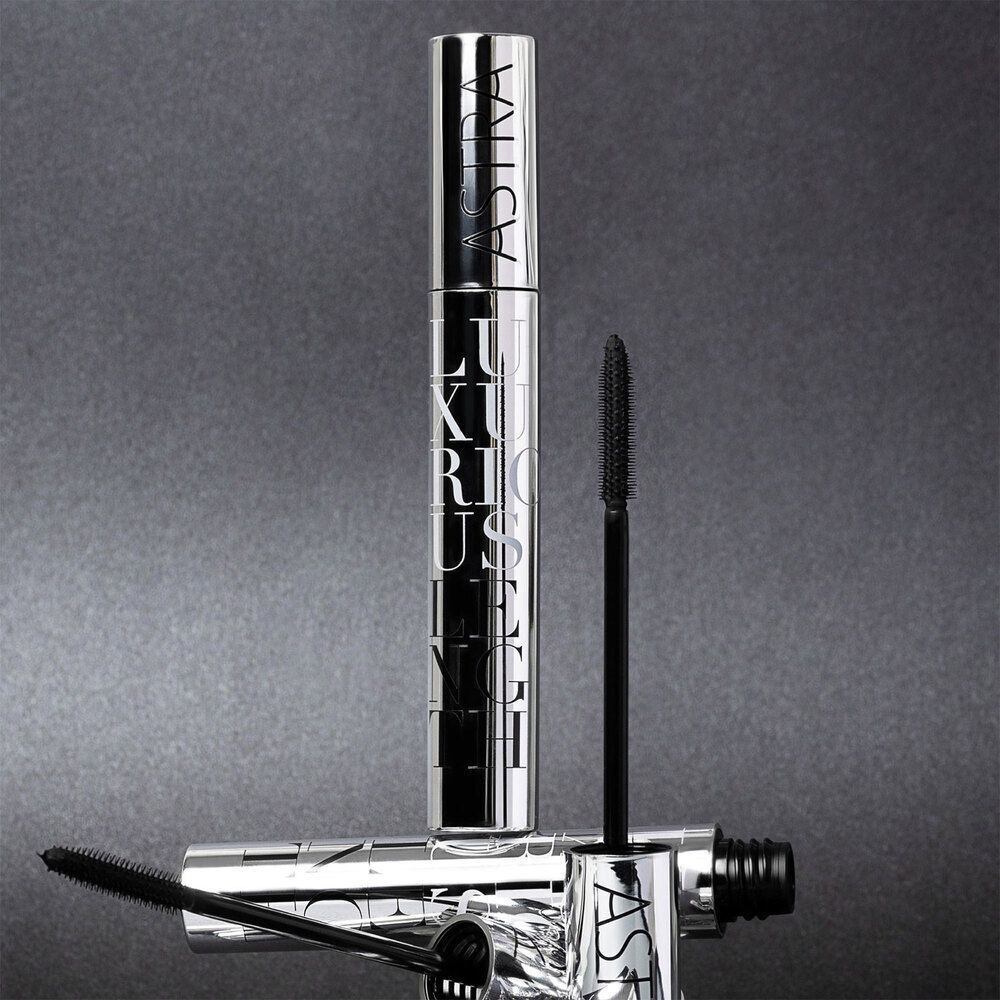Due tubetti di mascara argentati ASTRA con scritta LUXURIOUS LENGTH, uno in piedi, uno sdraiato. Pennelli visibili.