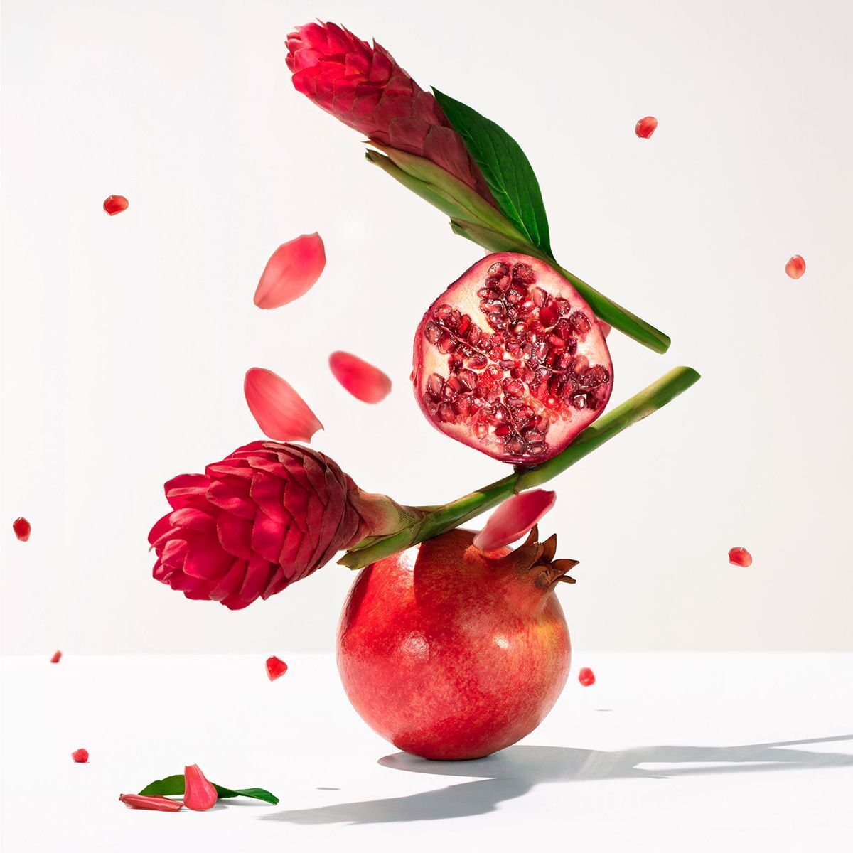 Un melograno, una metà di melograno tagliata, due fiori di zenzero e semi di melograno.