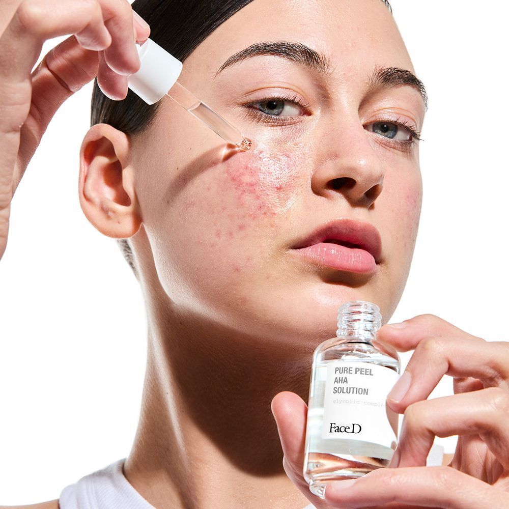 Una persona applica Face D Pure Peel AHA Solution con contagocce sulla pelle.