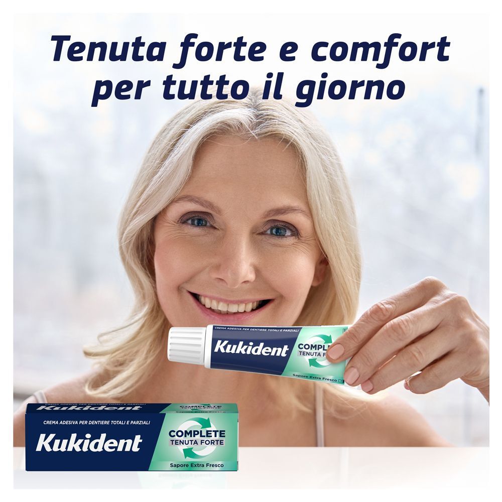 Donna tiene tubetto Kukident Complete Extra Fresco. Crema adesiva per protesi.