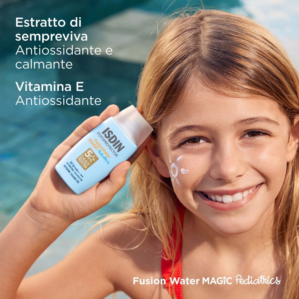 Un bambino tiene in mano un flacone di ISDIN Fotoprotector Fusion Water Magic Pediatrics Fluido (SPF 50) vicino a una piscina.