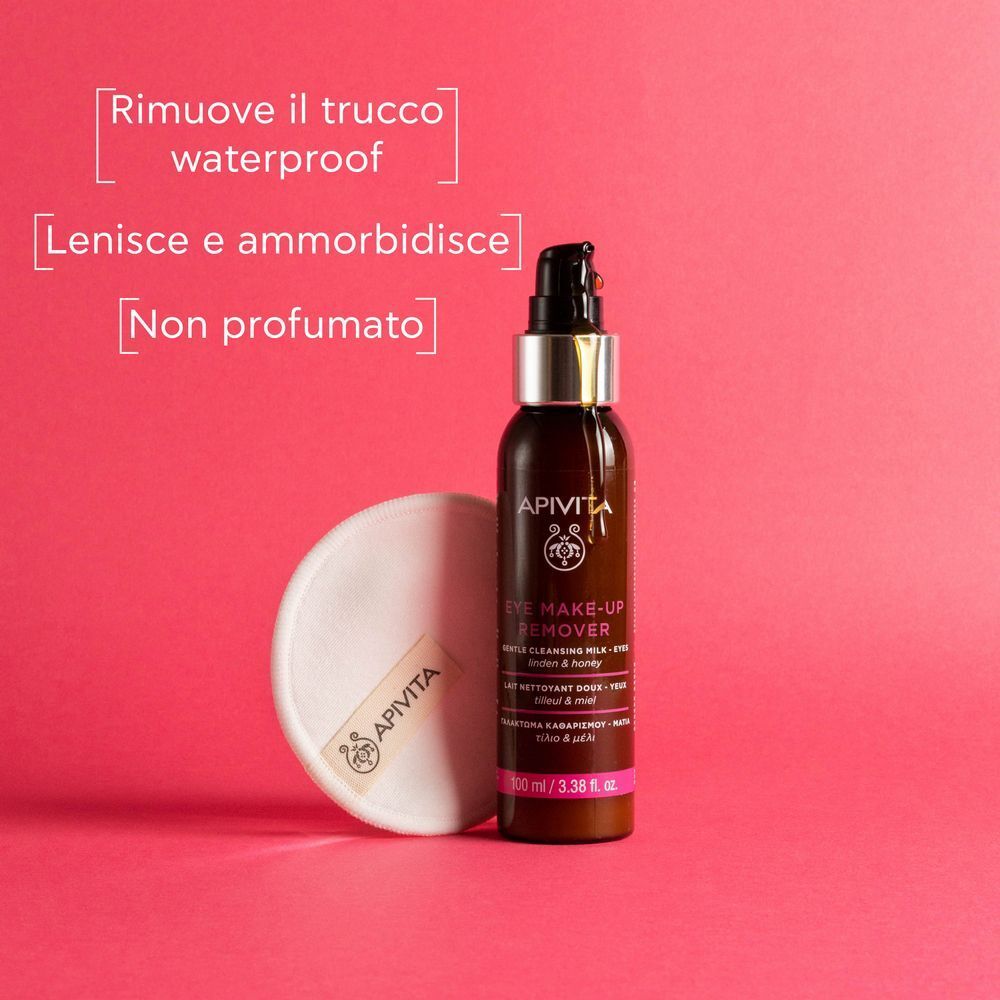 Flacone struccante occhi APIVITA e dischetto di cotone su sfondo rosa.