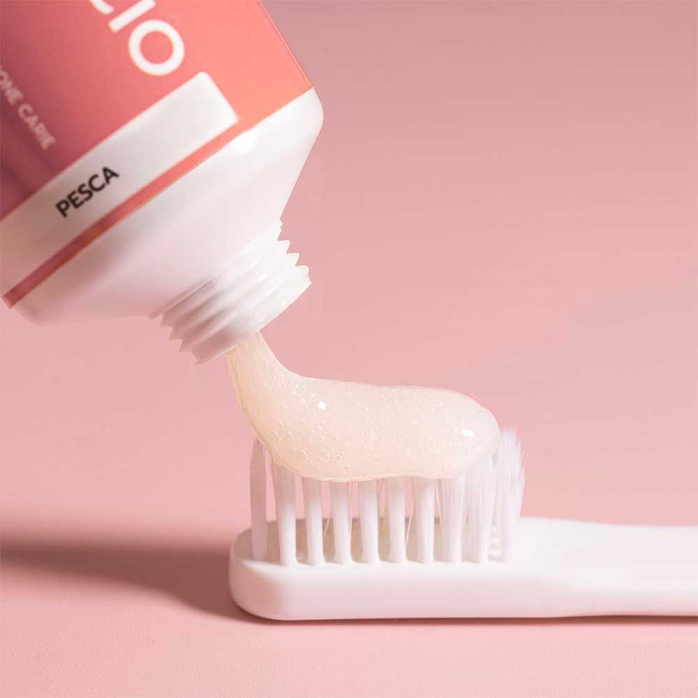 Geldis Dentifricio per denti sensibili, gusto pesca, applicato su uno spazzolino.